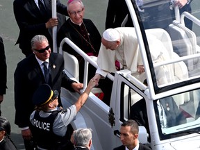 Pope Francis greets a police officer as he arrives for an open-air mass at Commonwealth Stadium in Edmonton, Canada, on July 26, 2022. - The Pope with be celebrating the feast of St. Anne, grandmother of Jesus, a day of particular reverence for Indigenous Catholics.