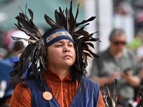 An indigenous faithful watches as Pope Francis arrives for an open-air mass at Commonwealth Stadium in Edmonton, Canada, on July 26, 2022. - The Pope will be celebrating the feast of St. Anne, grandmother of Jesus, a day of particular reverence for Indigenous Catholics.