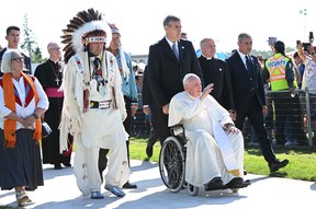 A member of the Alexis Nakota Sioux Nation walks alongside Pope Francis as he arrives to participate in the Lac Ste. Anne Pilgrimage and Liturgy of the Word at Lac Ste. Anne, northwest of Edmonton, Alberta, Canada, July 26, 2022.