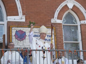 Archbishop Richard Smith blesses those attending with holy water before entering the church. Sacred Heart Church of the First Peoples was damaged by fire in the spring of 2020 and the reconstruction has been pushed along by a visit by Pope Francis in July 2022. The church was dedicated on July 17, 2022.