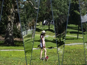 Natalia Mannarino and her dog are reflected in mirrors while enjoying the sunny morning at Boarden Park in Edmonton Alberta, July 10, 2022.