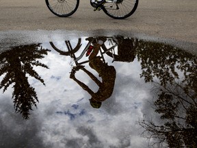 A cyclist is reflected in a large puddle at Hawrelak Park in Edmonton Alberta, July 4, 2022.