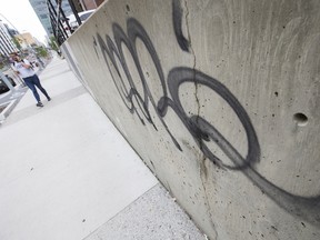 A pedestrian makes their way past graffiti along Jasper Avenue near 111 Street in Edmonton on Thursday, July 7, 2022. Edmonton police are seeking the public's help in tackling graffiti. In 2021, there were 157 reports of graffiti in the Downtown area, and 163 in the southwest. The other divisions had less than 100 reports each of graffiti last year.