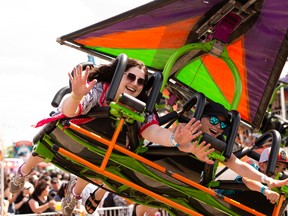 Postmedia reporter Lauren Boothby (left) rides the Cliff Hanger on the Midway at K-Days in Edmonton, on Saturday, July 23, 2022. Photo by Ian Kucerak