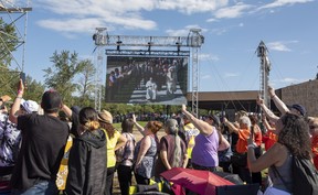 People watch a large screen as Pope Francis makes his way to the lake on Tuesday, July 26, 2022 at Lac Ste. Anne.   Pope Francis is visiting Canada to apologize to Indigenous survivors of abuse committed over decades at Catholic Church run residential schools.