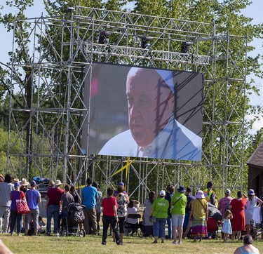 People watch a large screen as Pope Francis makes his way to the lake on Tuesday, July 26, 2022 at Lac Ste. Anne.   Pope Francis is visiting Canada to apologize to Indigenous survivors of abuse committed over decades at Catholic Church run residential schools.