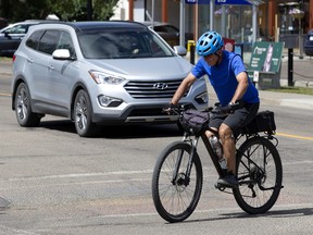 A cyclist makes their way through an intersection in Edmonton's Ritchie Neighbourhood, Tuesday, July 19, 2022. The city is trying to increase awareness of Edmonton's Safe Passing Distance Bylaw and how to pass people cycling and scootering safely on the street.