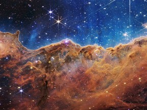 The "Cosmic Cliffs" of the Carina Nebula is seen in an image divided horizontally by an undulating line between a cloudscape forming a nebula along the bottom portion and a comparatively clear upper portion, with data from NASA's James Webb Space Telescope, a revolutionary apparatus designed to peer through the cosmos to the dawn of the universe and released July 12, 2022. Speckled across both portions is a starfield, showing innumerable stars of many sizes. NASA, ESA, CSA, STScI, Webb ERO Production Team/Handout via REUTERS THIS IMAGE HAS BEEN SUPPLIED BY A THIRD PARTY.