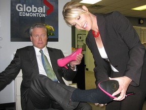 Lynda Steele helps fellow Global News co-anchor Gord Steinke into high-heeled shoes to join 150 other heeled men walking around Churchill Square to bring awareness to women's shelters.