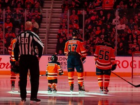 Five-year-old Scotiabank Skater Ben Stelter stands with the Edmonton Oilers and the San Jose Sharks during the national anthems at a NHL game at Rogers Place in Edmonton, on Thursday, March 24, 2022.