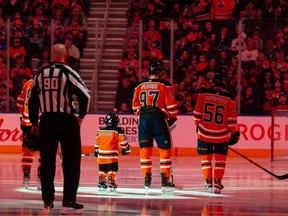 Five-year-old Scotiabank Skater Ben Stelter stands with the Edmonton Oilers and the San Jose Sharks during the national anthems at an NHL game at Rogers Place in Edmonton on March 24, 2022.