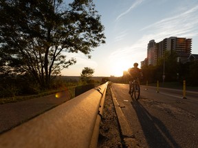 A cyclist exercises on Victoria Park Road near Grant Notley  Park as the sun sets in Edmonton, on Friday, Aug. 12, 2022.