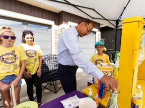 Mayor Amarjeet Sohi buys a lemonade at the Chapman family lemonade stand during the Ninth Annual Simply Supper Lemonade Stand Day in support of the Stollery Children's Hospital in Edmonton, on Sunday, Aug. 28, 2022.