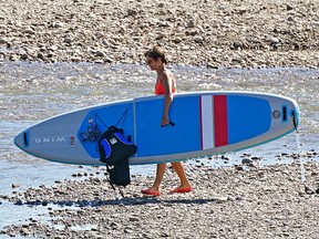 A woman prepares to launch her paddle board from the "Accidental Beach" on the North Saskatchewan River near downtown Edmonton on Thursday August 18, 2022. Environment Canada has issued a heat warning for the Edmonton region with temperatures expected to hover around 30C degrees.