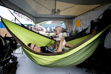 Volunteer Cara Duffield entertains Lewis Gaus, 6 months-old, in the Schlepper tent as Lewis' mother volunteers nearby at the Edmonton Folk Music Festival, Saturday Aug. 6, 2022.