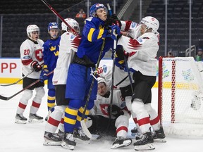 Sweden's Simon Edvinsson (7) and Switzerland's Attilio Biasca (17) rough it up during second period IIHF World Junior Hockey Championship action in Edmonton on Wednesday, Aug. 10, 2022.