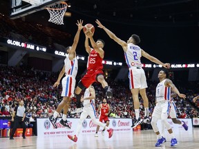 Canada's Trae Bell-Haynes (25) drives to the net between Dominican Republic's Gelvis Solano (4) and Rigoberto Mendoza (2) during second half FIBA international men's World Cup basketball qualifying action, in Hamilton, Ont., on July 1, 2022.
