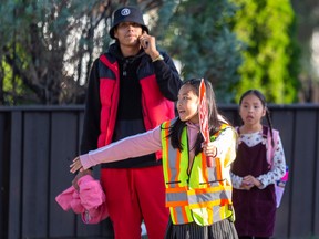 AMA school safety patrols Mayel Bernardo, 11, a Grade 6 student, helps students and parents cross the street safely at  Our Lady of Peace Catholic Elementary School on the first day of school on Wednesday, Aug. 31, 2022 in Edmonton.