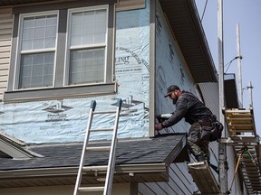 A worker with Risling Exteriors replaces the vinyl sidings that were damaged by a hail storm with fibre cement sidings on a house in Skyview on Monday, April 18, 2022. Fibre cement sidings are more resistant to hail damage and fire.