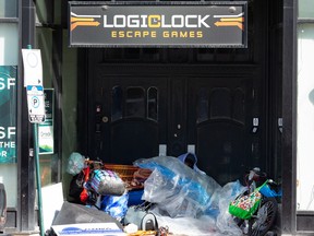 A homeless person uses the entryway of a closed business on Jasper Avenue near 104 Street to sleep with their belongings in Edmonton, on Thursday, April 21, 2022.