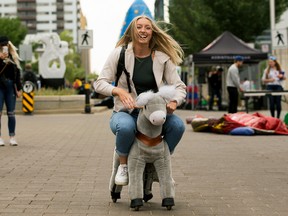 A student rides a plush horse while taking part in the Downtown Campus Block Party for MacEwan University and NorQuest College students, along 108 Street between 102 Avenue and 104 Avenue, in Edmonton, Wednesday, Sept. 7, 2022.
