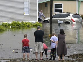 Residents check on one another in a flooded neighborhood in the aftermath of Hurricane Ian, Thursday, Sept. 29, 2022, in Orlando, Fla.