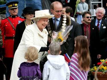 May 25, 2005. Queen Elizabeth II gets a bouquet of flowers from a trio of young admirers while mayor Stephen Mandel looks on during the royal walk-about in Winston Churchill Sq., in Edmonton on May 25, 2005.