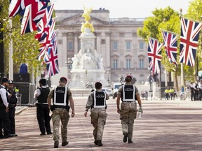 Civilian and Military Police walk the perimeter at the gates of Buckingham Palace in London, Friday, Sept. 16, 2022.