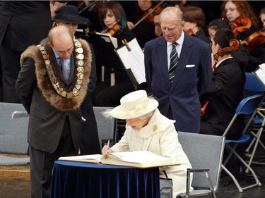 Edmonton mayor Stephen Mandel and Prince Philip look on as Queen Elizabeth II signs the City of Edmonton Distinguished Visitors Book in Winston Churchill Square on Wednesday, May 25, 2005. The Edmonton Youth Orchestra plays in the background.