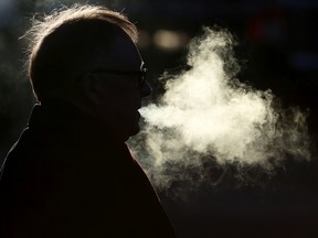 A smoker exhales while waiting to cross 109 Street at Jasper Avenue, in Edmonton Alta. File photo.