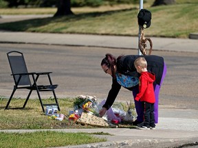 A woman and her child pay their respects for Brian Berland on Thursday September 8, 2022, at the intersection where he was murdered. He was the stabbing victim who died following a random attack on the street in northeast Edmonton yesterday. Two other victims are in serious condition.