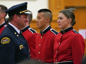 Recruit firefighters Kenna Sadler, right, and Daniel Nguyen, middle, stand at attention as Edmonton Fire Chief Joe Zatylny, left, conducts an inspection during a graduation ceremony of 37 new firefighters at the Italian Cultural Centre in Edmonton on Thursday Oct. 27, 2022. Sadler was the lone woman in the graduating class.