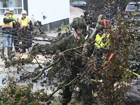 Cpl. Owen Donovan of the Cape Breton Highlanders removes brush under the direction of Nova Scotia Power officials along Steeles Hill Road in Glace Bay, N.S., Monday, Sept. 26, 2022. Defence Minister Anita Anand says there are now 700 military members in Atlantic Canada helping with the cleanup after post-tropical storm Fiona left much of the region in tatters.