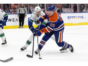 The Edmonton Oilers' Ryan Nugent-Hopkins (93) battles the Vancouver Canucks' Nils Aman (88) during first period NHL action at Rogers Place in Edmonton on Wednesday, Oct. 12, 2022.