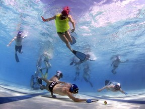 Players battle for the puck as a referee, above, watches during a game of underwater hockey.