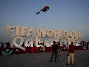 People pose for a photograph with a sign reading in English" Fifa World Cup, Qatar 2022" at the corniche in Doha, Qatar, Friday, Nov. 11, 2022.