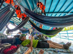 Foreign and Peruvian tourist rest in the boat where they have been detained at the Cuninico community in Loreto, north of Peru, on November 4, 2022. - Indigenous people in Peru's Amazon detained a group of foreign and Peruvian tourists traveling on a river boat to protest the lack of government aid following an oil spill in the area, local media reported Thursday.