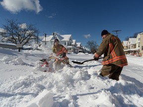 Firefighters Larry McPhail and Nick Eoanno clear hydrants after an intense lake-effect snowstorm that impacted the area on November 20, 2022 in Buffalo, New York.