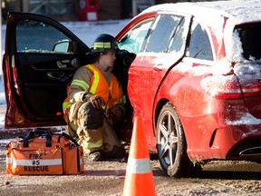 A firefighter sits with a motorist at the scene of a two vehicle collision along 82 Avenue at 95 Street, in Edmonton Thursday, Nov. 3, 2022. Photo By David Bloom