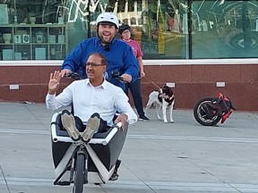 Edmonton Mayor Amarjeet Sohi rides into the cargo area on an electric bike ridden by the city's coun. Michael Jans.photo from twitter