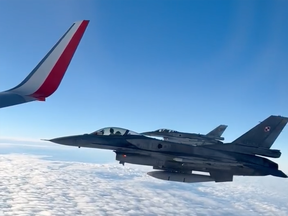 Two F-16s follow closely behind a jetliner carrying Poland's national men's soccer team.