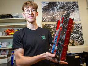 Thomas Ganley, AlbertaSat project manager, holds a replica of the satellite he helped in developing, Wednesday, Nov. 24, 2022. The Ex-Alta 2, a satellite designed and built by University of Alberta students, is on the move this week to the Canadian Space Agency en-route to its final destination, space.