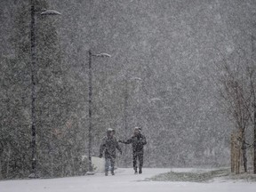 Heavy snow falls as a man jogs on a pathway at Central Park in Burnaby, B.C., on Tuesday, November 29, 2022. Snowfall, winter storm and arctic outflow warnings are in effect for most of British Columbia as a powerful storm packing frigid winds move through the province.