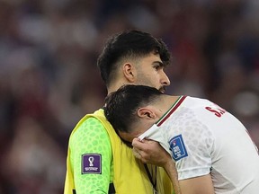Iran's midfielder #06 Saeid Ezatolahi (R) cries as he is comforted by Iran's goalkeeper #22 Amir Abedzadeh at the end of the Qatar 2022 World Cup Group B football match between Iran and USA at the Al-Thumama Stadium in Doha on November 29, 2022.