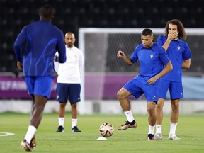 Kylian Mbappe of France passes the ball as Matteo Guendouzi reacts during the France Training Session at Al Sadd SC on December 13, 2022 in Doha, Qatar.