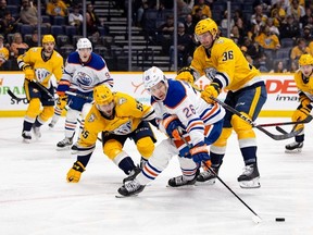 Mattias Janmark (26) of the Edmonton Oilers tries to control the puck against Roland McKeown (55) and Cole Smith (36) of the Nashville Predators during the second period at Bridgestone Arena on Dec. 13.