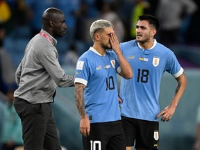 Uruguay's midfielder #10 Giorgian De Arrascaeta (C) and Uruguay's forward #18 Maximiliano Gomez (L) react as Ghana's coach Otto Addo approaches them at the end of the Qatar 2022 World Cup Group H football match between Ghana and Uruguay at the Al-Janoub Stadium in Al-Wakrah, south of Doha on December 2, 2022.