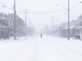 A man crosses a road during a snowstorm in Toronto on Friday, December, 23, 2022. A winter storm warning is in place for most of southern Ontario.