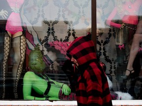 A sexy Grinch looks at passers-by from the window display at Nightshade Corsets, 8128 Gateway Blvd., Friday, December 23, 2022. Photo by David Bloom