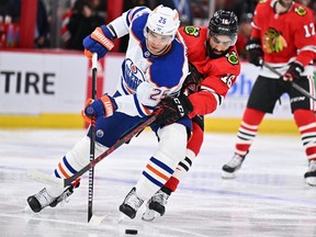 Nov 30, 2022; Chicago, Illinois, USA;  Edmonton Oilers defenseman Darnell Nurse (25) and Chicago Blackhawks forward Jujhar Khaira (16) battle for control of the puck in the second period at United Center. Mandatory Credit: Jamie Sabau-USA TODAY Sports